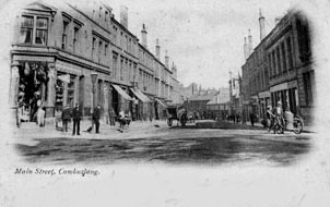Main Street at the Cross cira 1897 - Banner over Scoular's door and flags suggest photo taken for Diamond Jubilee of Queen Victoria - Card date 1902